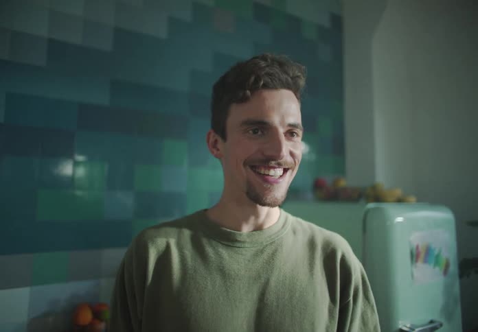 A man turns around in the kitchen talking