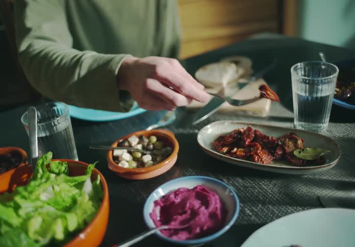 A man uses a fork to pick up a piece of food out of a dish