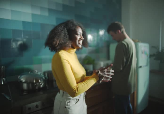 A man is cooking while a woman is handed a drink
