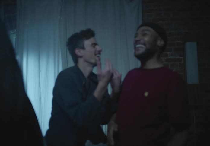 Friends dance together in dark room lit by party lights