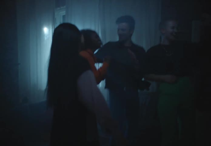 Friends dance at house party lit by flashing light