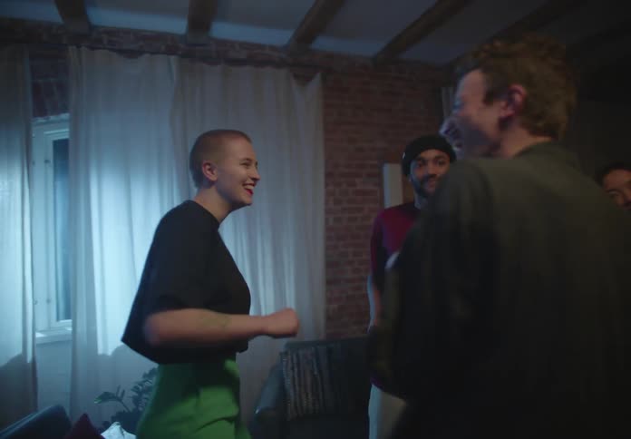 A group of friends dance together in their living room