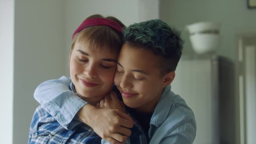 Woman smiles and leans cheek against the person hugging her