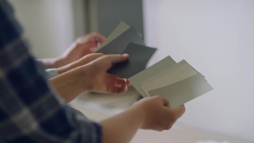 Female hands holding several paint swatches deciding on color