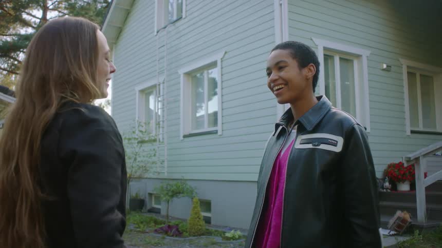 A woman runs out of her home and hugs a woman in her driveway that has luggage