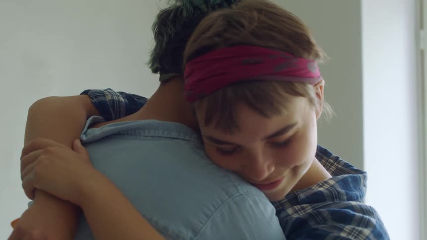 A woman smiles while embracing a man indoors during the day