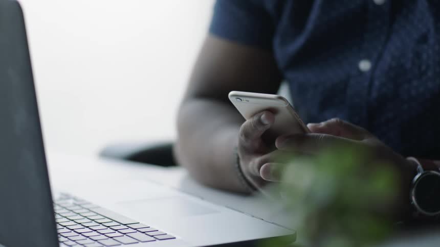 A person is using a phone by a laptop