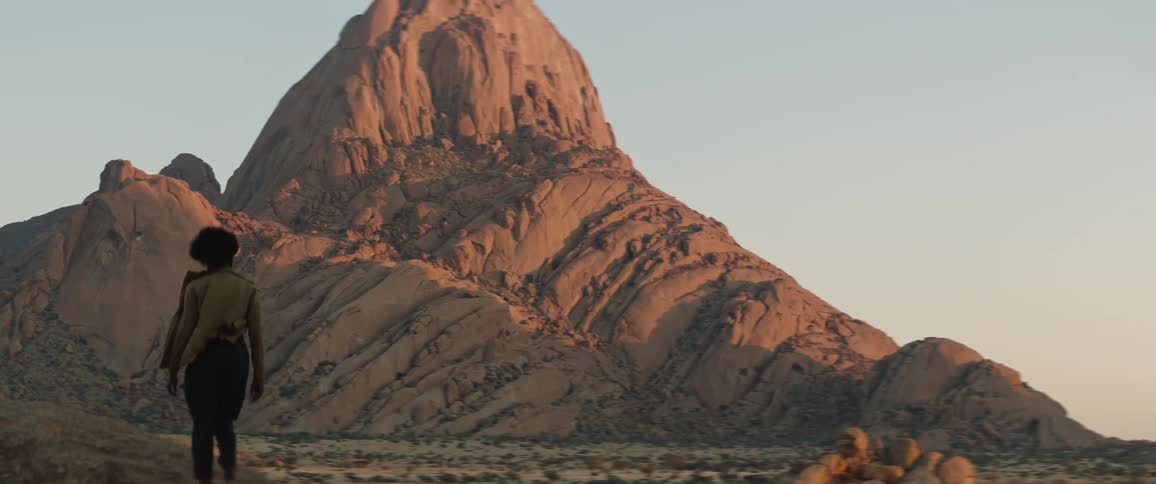 Woman walks across plain toward mountain