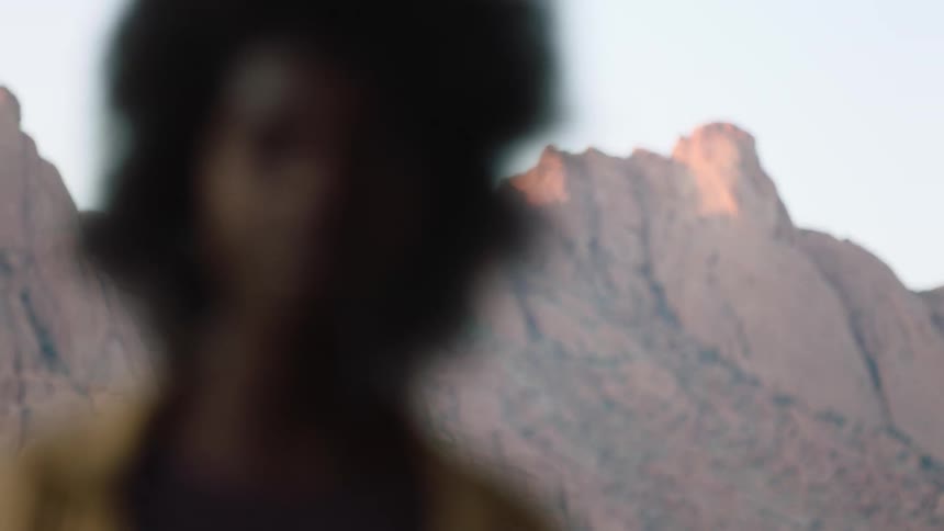 Young black woman with afro outdoors in desert looking into the camera