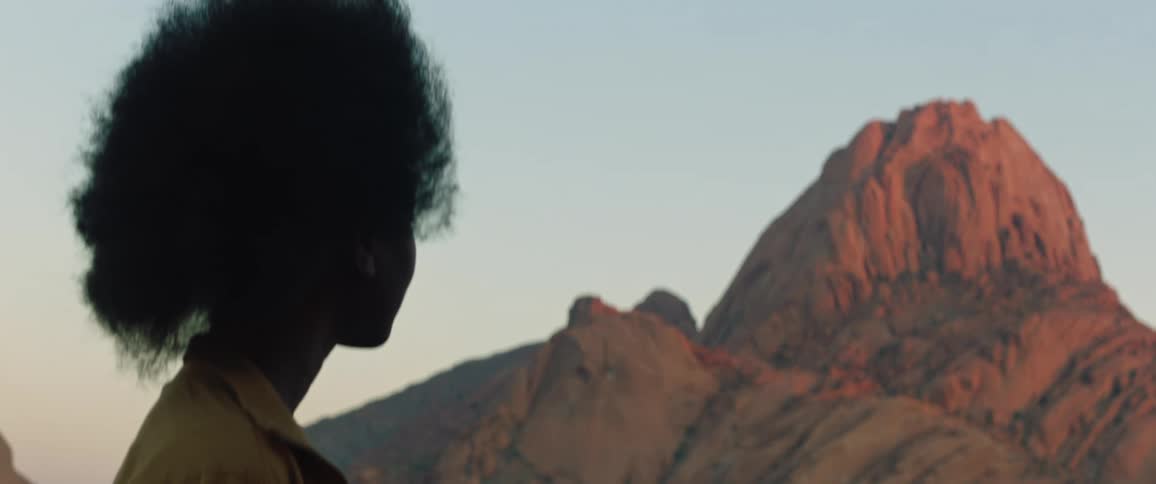 A young black woman is looking at mountains