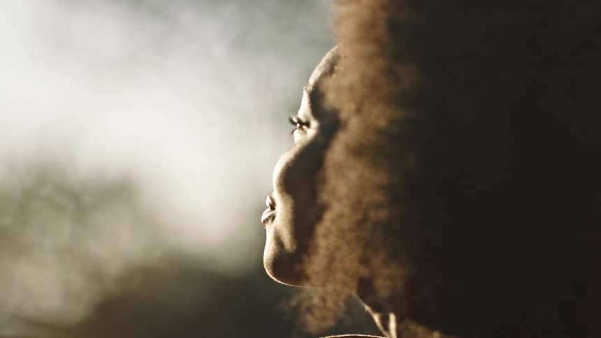 Close up portrait of a black woman enjoying the sunshine and wind turns to look into camera