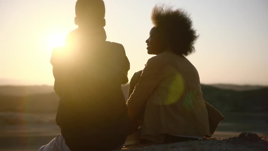 Man and woman sit together watching the sunrise