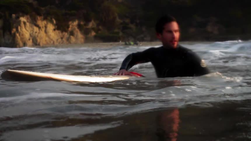 A man holds on to his surfboard in the water