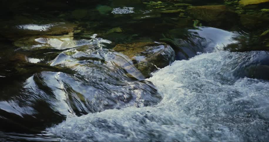 Clear river water rushes over large rocks