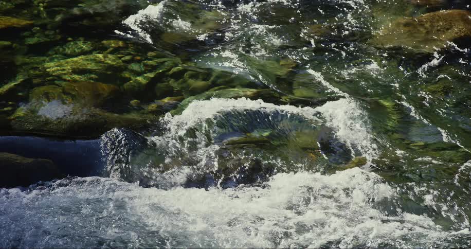 Clear translucent water flowing over the rocks on a river at morning