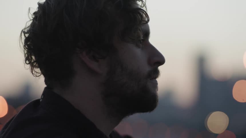 A man is sitting looking forward at sunset