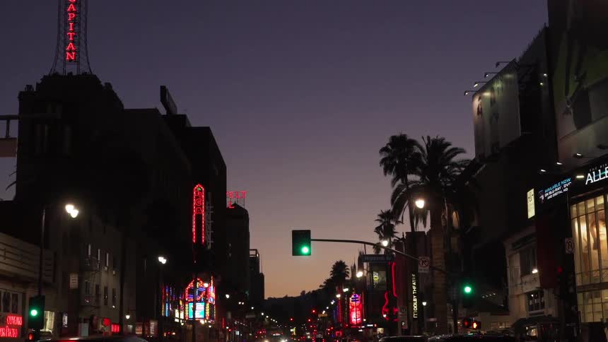 Slowly moving down a lit city street at sunset