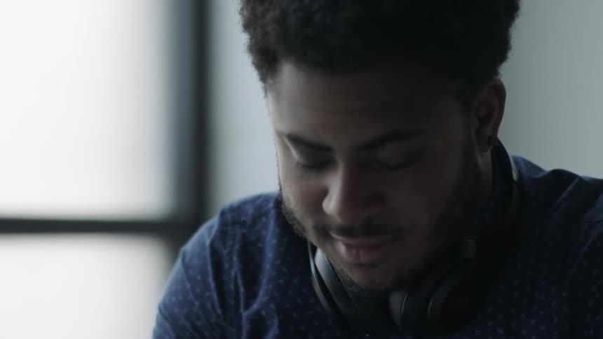 A man with headphones around his neck is looking down