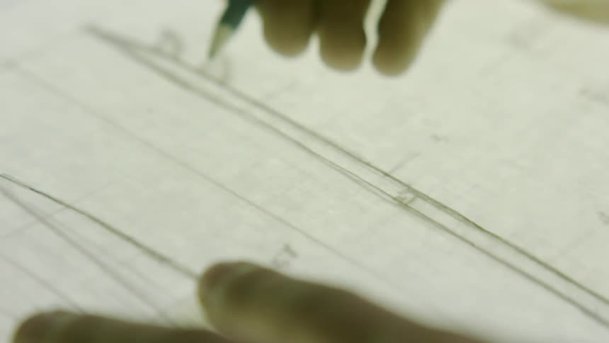 A person is writing lines on a diagram with a pencil