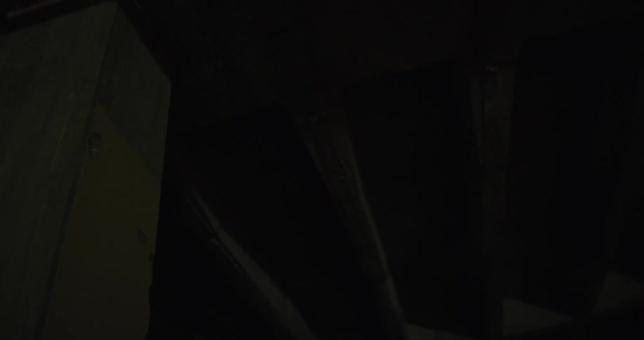 A red laser flashes on and off in a dark basement