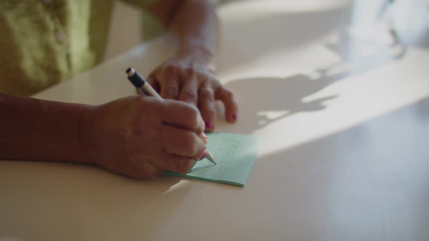 A person is writing a note on the table