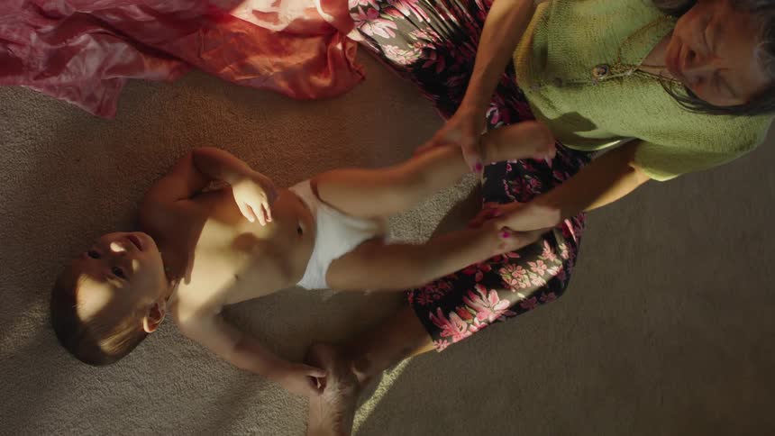 A woman is having fun with her grandson on the floor