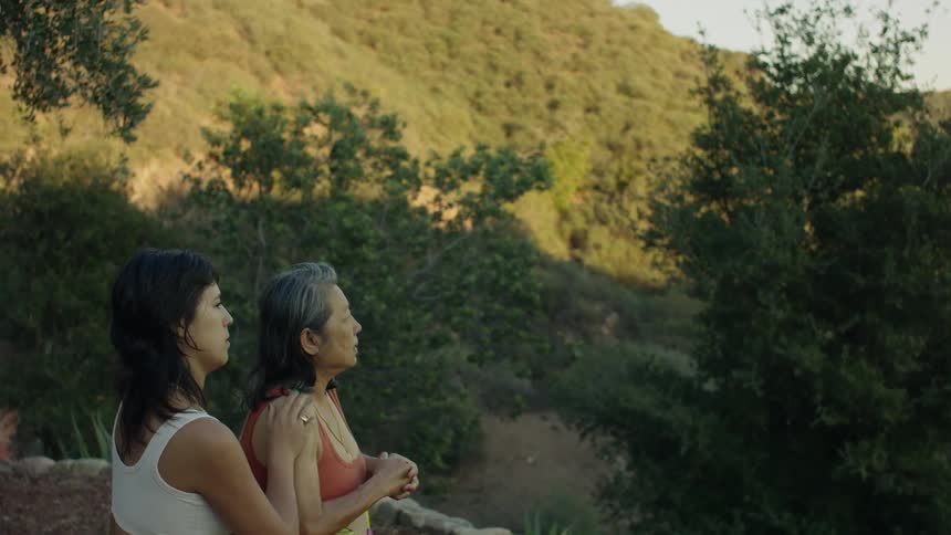 A young woman massaging her grandmothers arm outside near trees