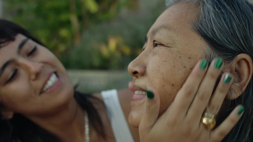 Younger woman applies lotion to older womans face