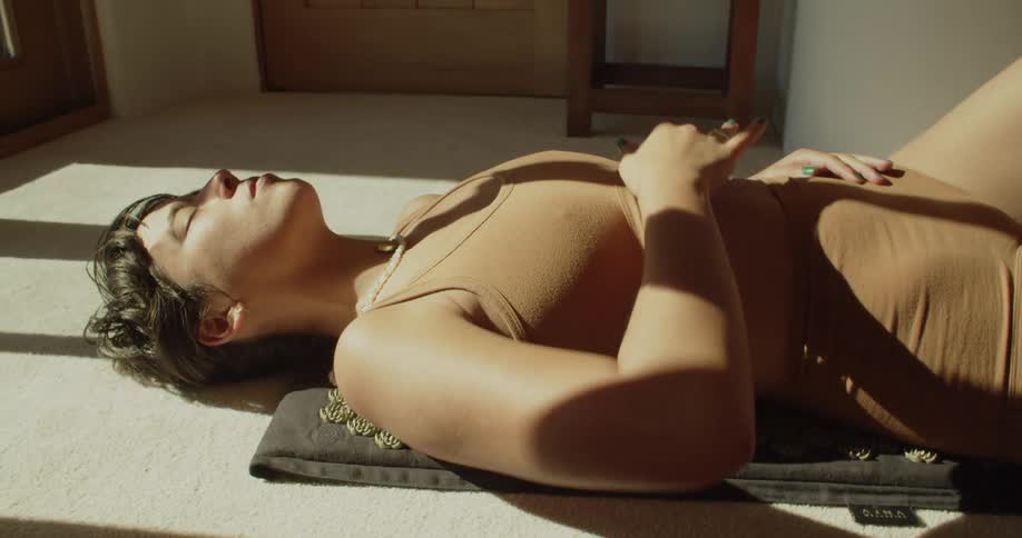 A woman rubbing a ball on her chest while stretching and doing yoga on the floor