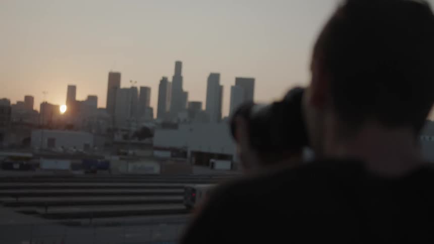 A man photographs a city at dawn
