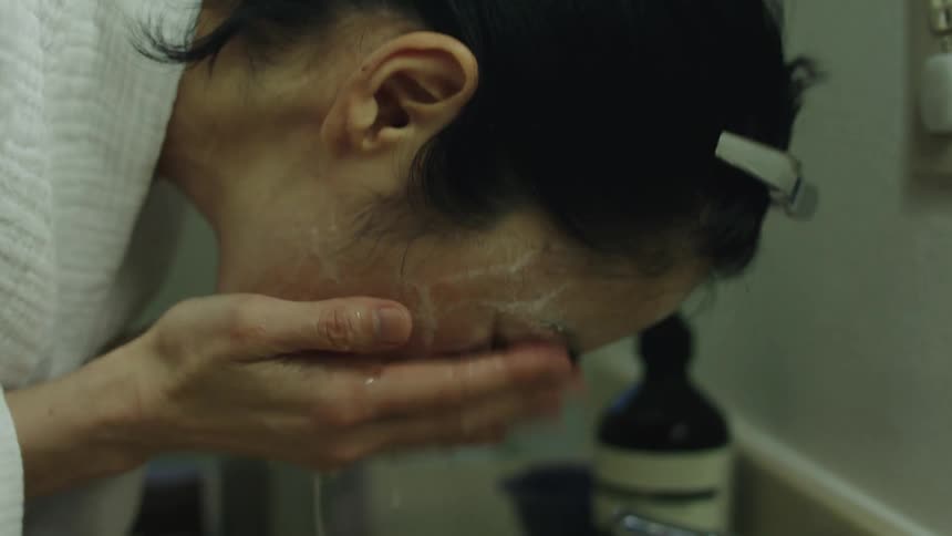 Woman cleans and washes face mask with water in the bathroom