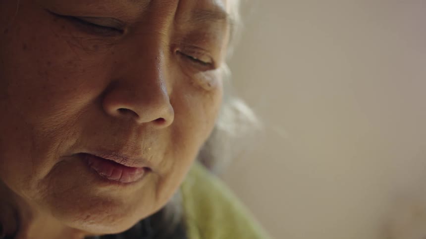 Close up of the face of an elderly woman inside a room