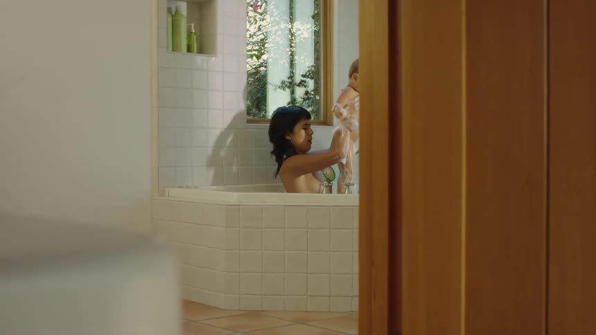 Mother takes a bathtub bath with her baby in the bathroom at home
