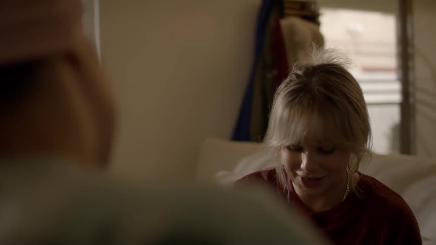 Two women are sitting in a living room and laughing together