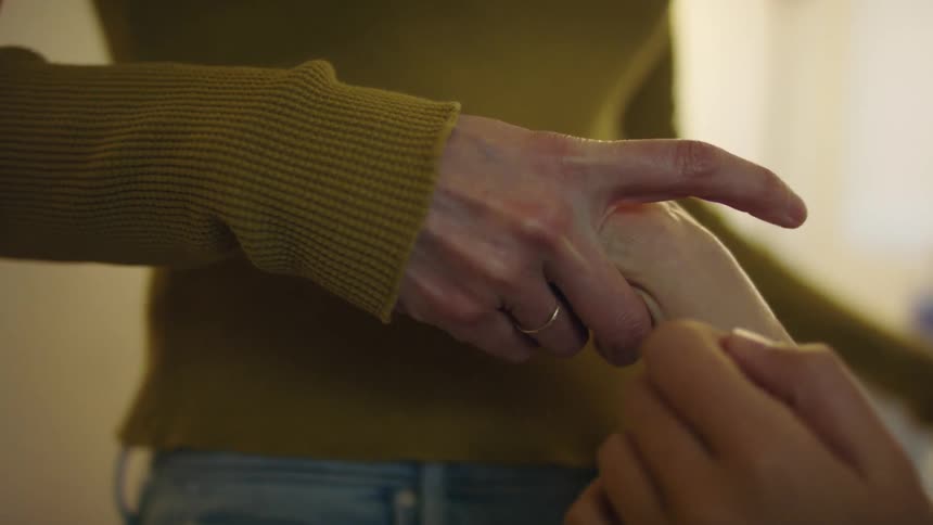 Young woman smells the perfume a friend applied to her wrist