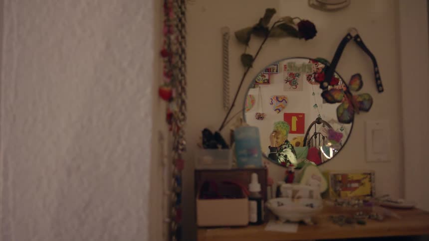 A woman is sitting in her room and putting on makeup