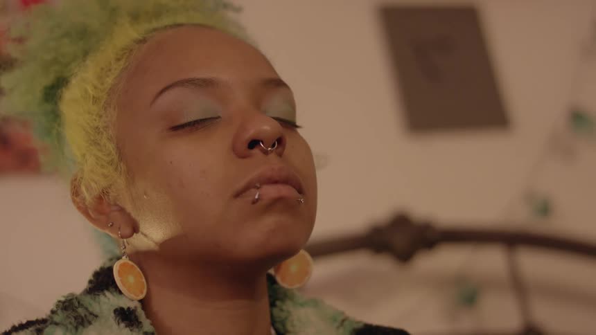 A young black woman with yellow hair is getting her makeup donei