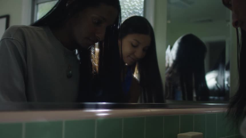 Two girls are in a bathroom and washing their hands