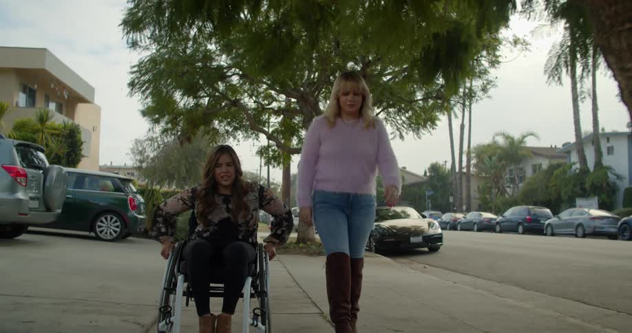 Two women travel down the sidewalk together