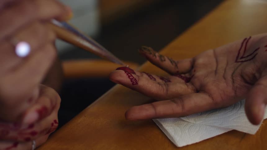 Someone is having designs painted on their fingers with henna paint