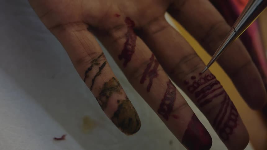 A henna tattoo is being applied to a man's hand