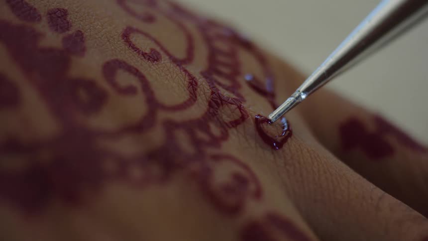 A person is receiving a red tattoo