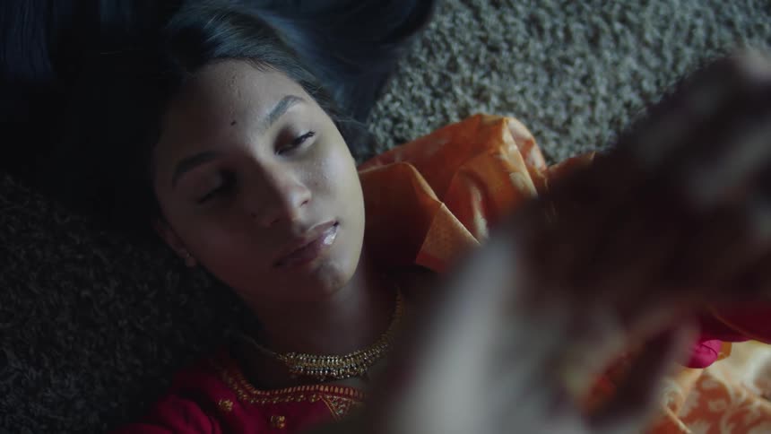 Young indian woman relaxing over a rug in the floor wearing a traditional red saree