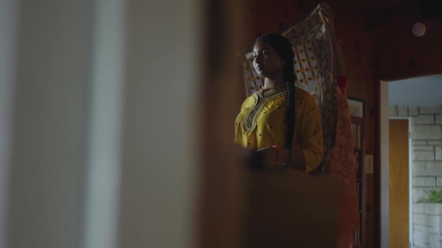 Indian mother helps daughter to dress in the traditional sari dress at home