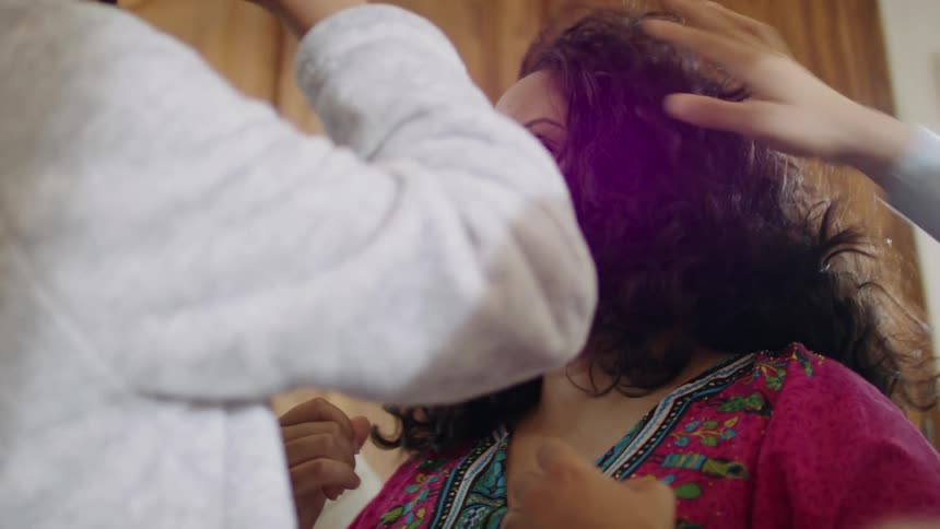 People are in a kitchen and fixing someones hair