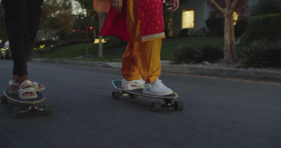 Group of teenagers skateboarding on the neighborhood street at evening