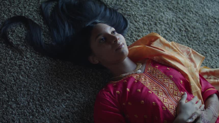A woman is resting on the ground and wearing a sari