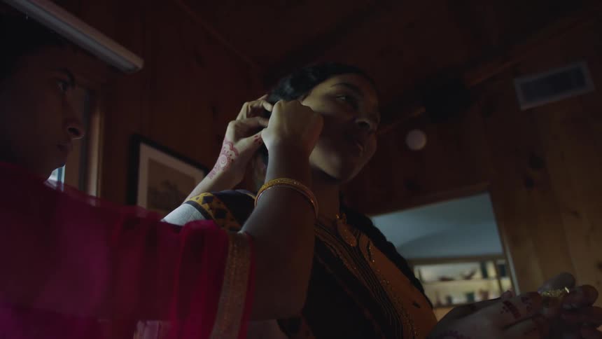 A girl puts an earring on her teenage sister