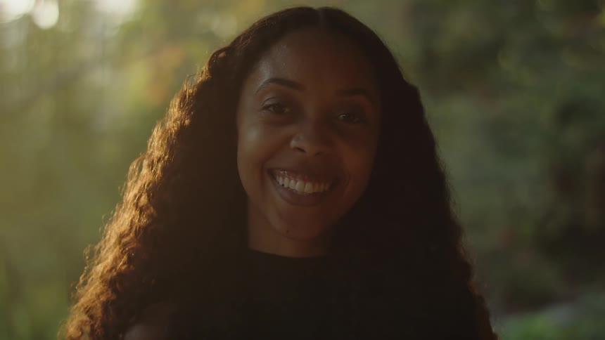 A woman is smiling outdoors in spring