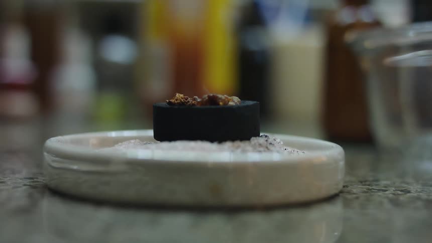 Close up of incense burning over a round charcoal puck on the countertop
